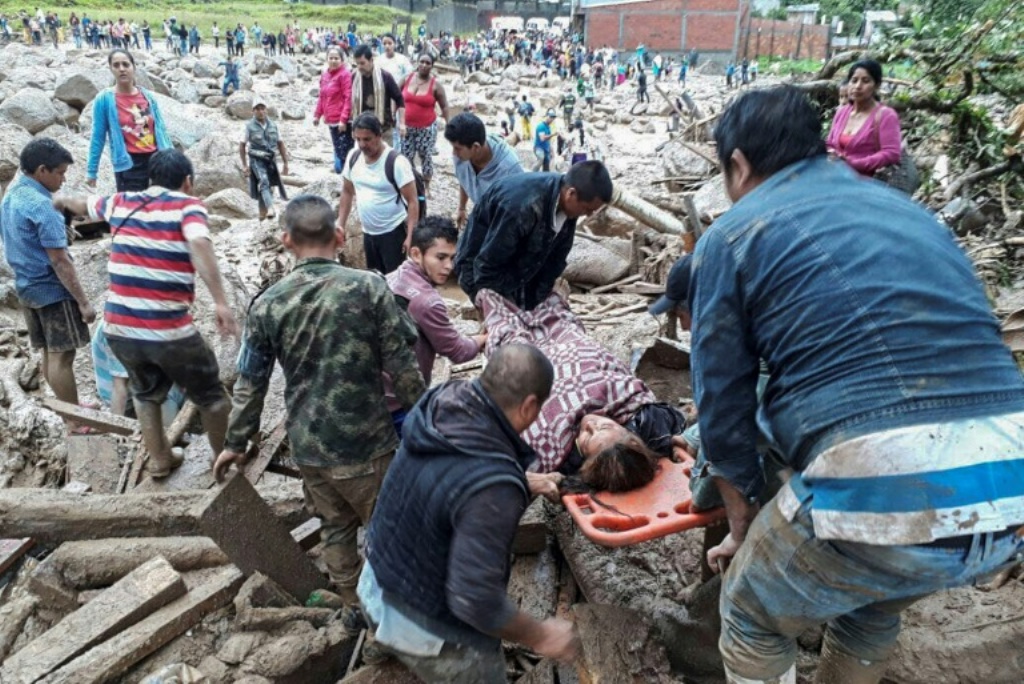 Volunteers help carry a woman who was trapped under debris following mudslides in Mocoa, Putumayo department, on April 1, 2017/ AFP.