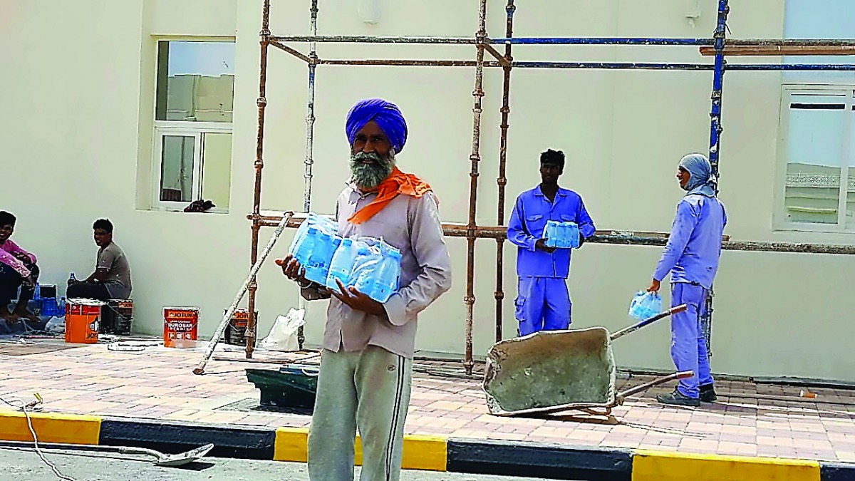 Workers receive water bottles at a construction site.