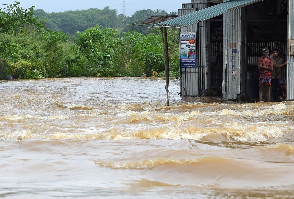 Sri Lankan residents stand in the doorway of a building surrounded by floodwaters in the suburb of Kaduwela in the capital Colombo on May 26, 2017. AFP / Ishara S. Kodikara 