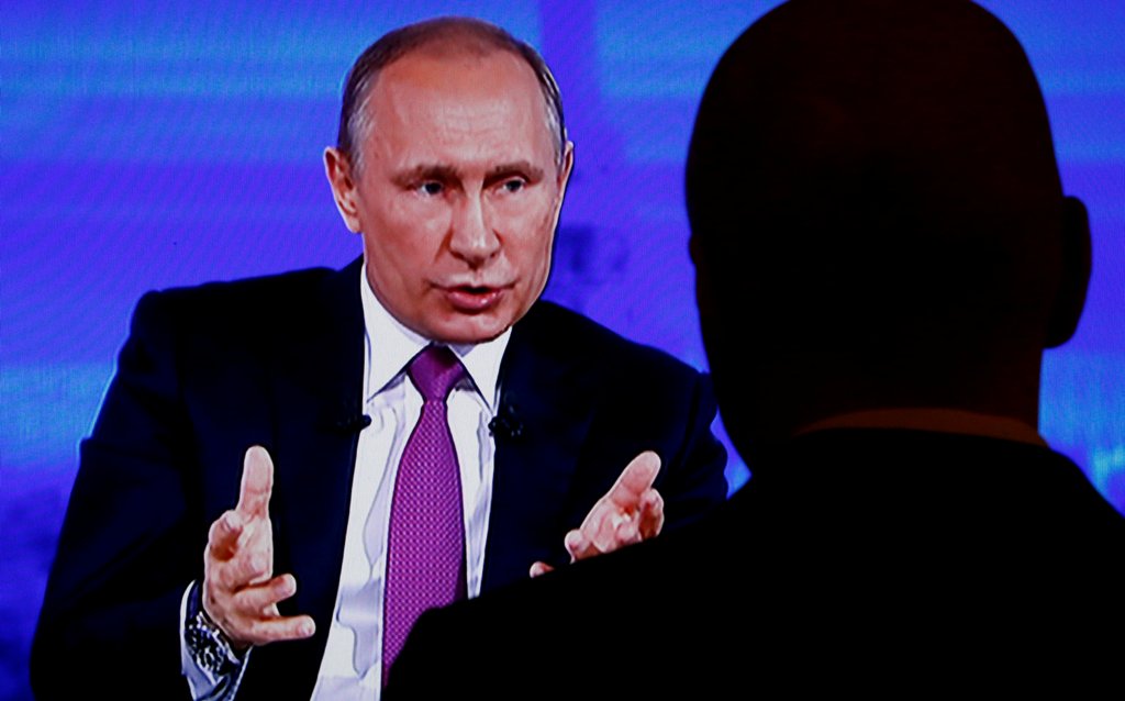 A journalist watches a live broadcast on an electronic screen showing nationwide call-in attended by Russian President Vladimir Putin, in Moscow, Russia, June 15, 2017. REUTERS/Sergei Karpukhin