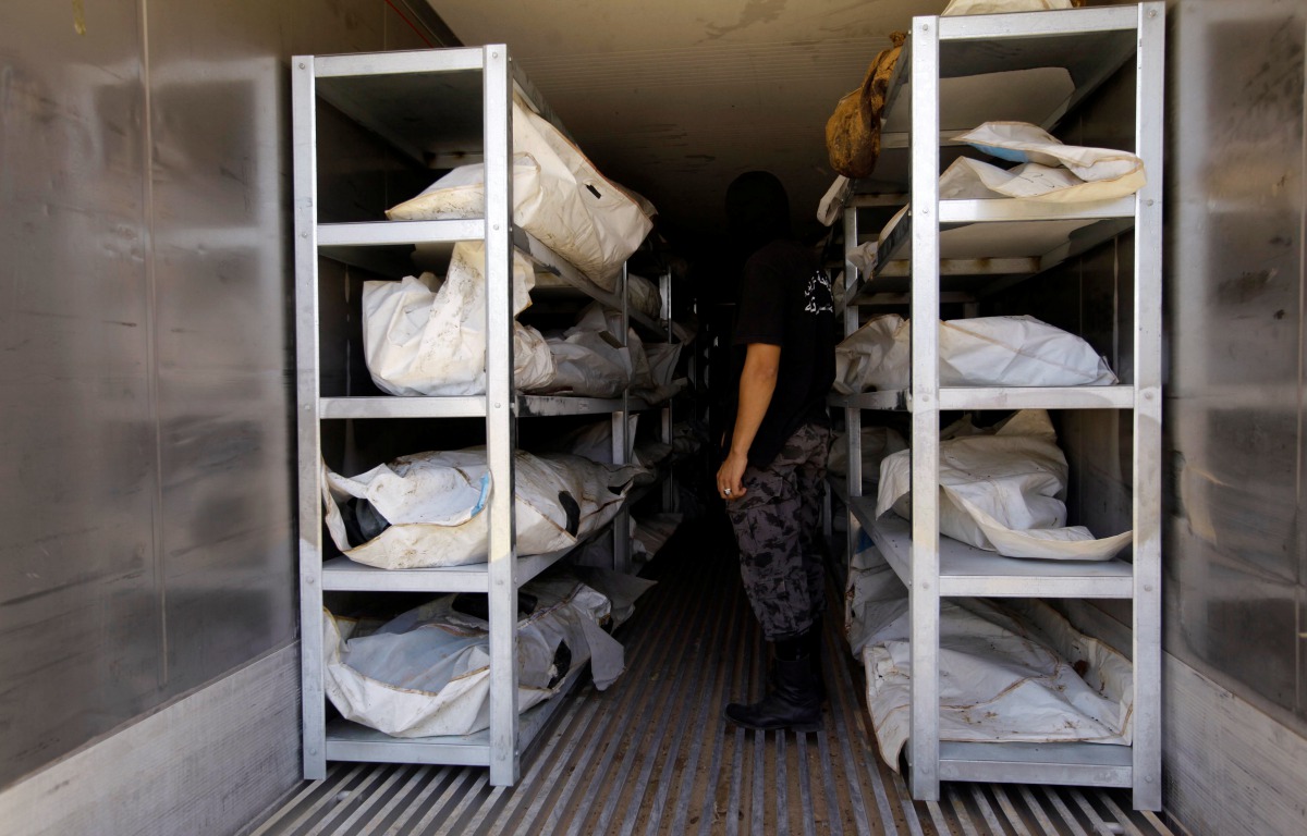 A member of Libyan anti-crime service stands next to dead bodies of Islamic State militants, at a morgue in Misrata, Libya July 22, 2017. Reuters/Ismail Zitouny
