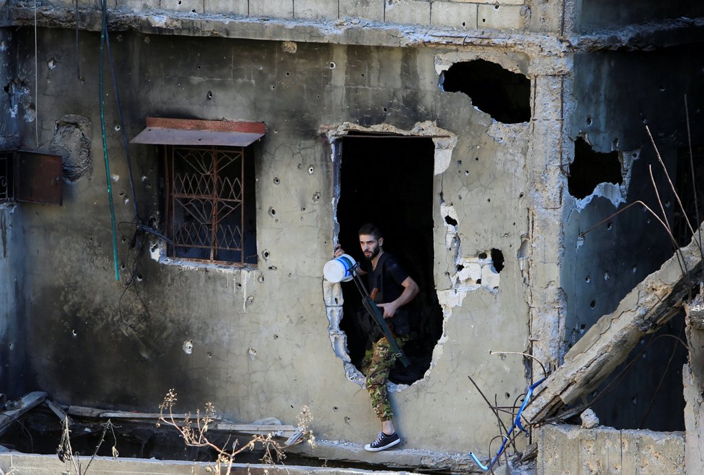 A Palestinian Fatah fighter walks through a hole in a wall inside the Ain el-Hilweh refugee camp near Sidon, southern Lebanon, August 23, 2017. REUTERS/Ali Hashisho
