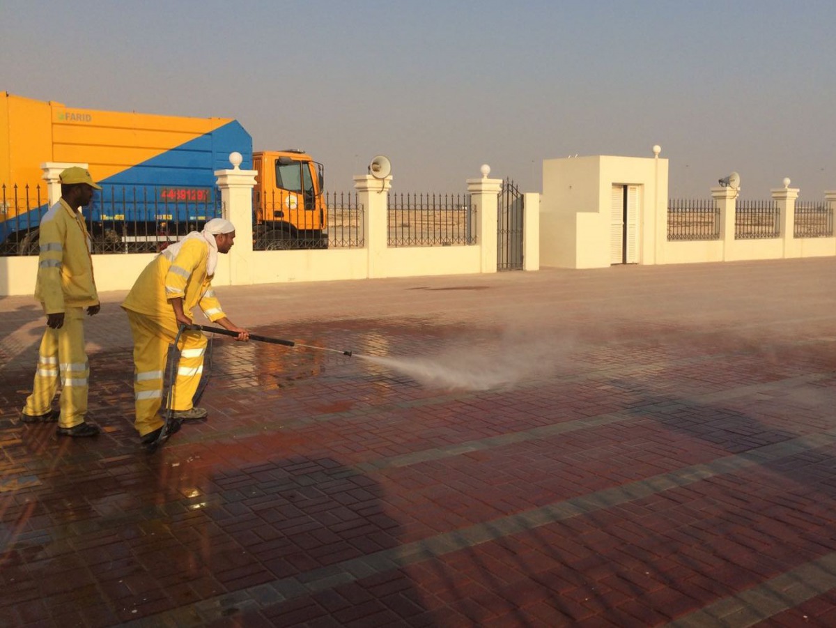Workers cleaning a Eid prayer yard.
