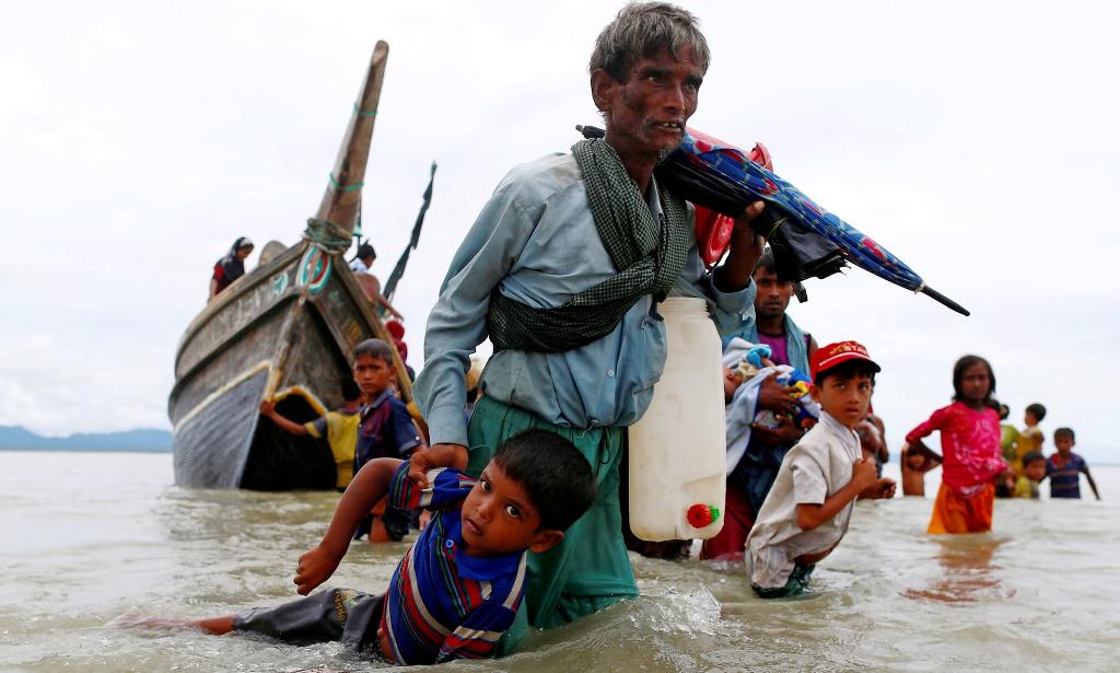  A Rohingya refugee pulls a child as they walk to shore after crossing the Bangladesh-Myanmar border by boat on Sunday. Photograph: Danish Siddiqui/Reuters.