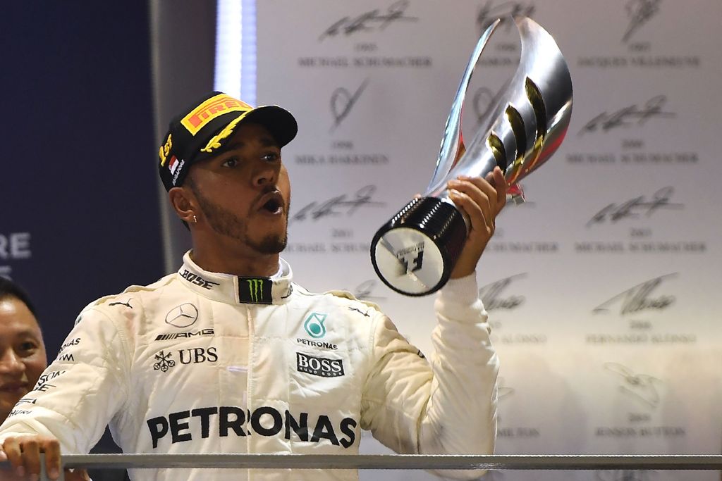 Mercedes' British driver Lewis Hamilton celebrates on the podium after winning the Formula One Singapore Grand Prix in Singapore on September 17, 2017. / AFP / MANAN VATSYAYANA
