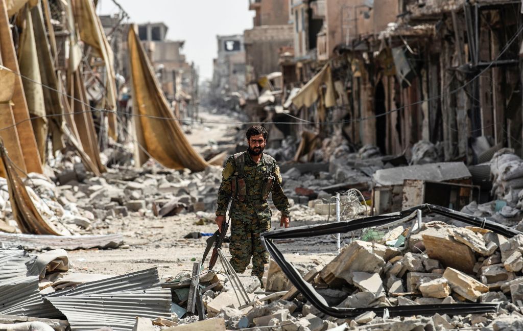A member of the Syrian Democratic Forces (SDF) walks through the debris in the old city centre on the eastern frontline of Raqa on September 25, 2017.   AFP / BULENT KILIC
