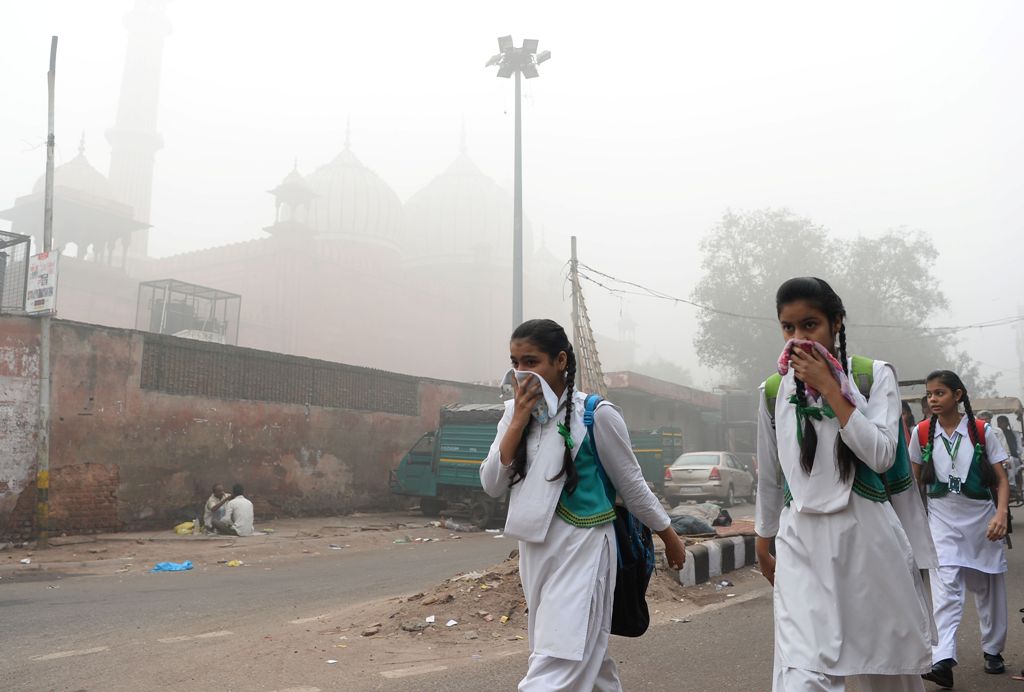 Indian schoolchildren cover their faces as they walk to school amid heavy smog in New Delhi on November 8, 2017. / AFP / SAJJAD HUSSAIN
