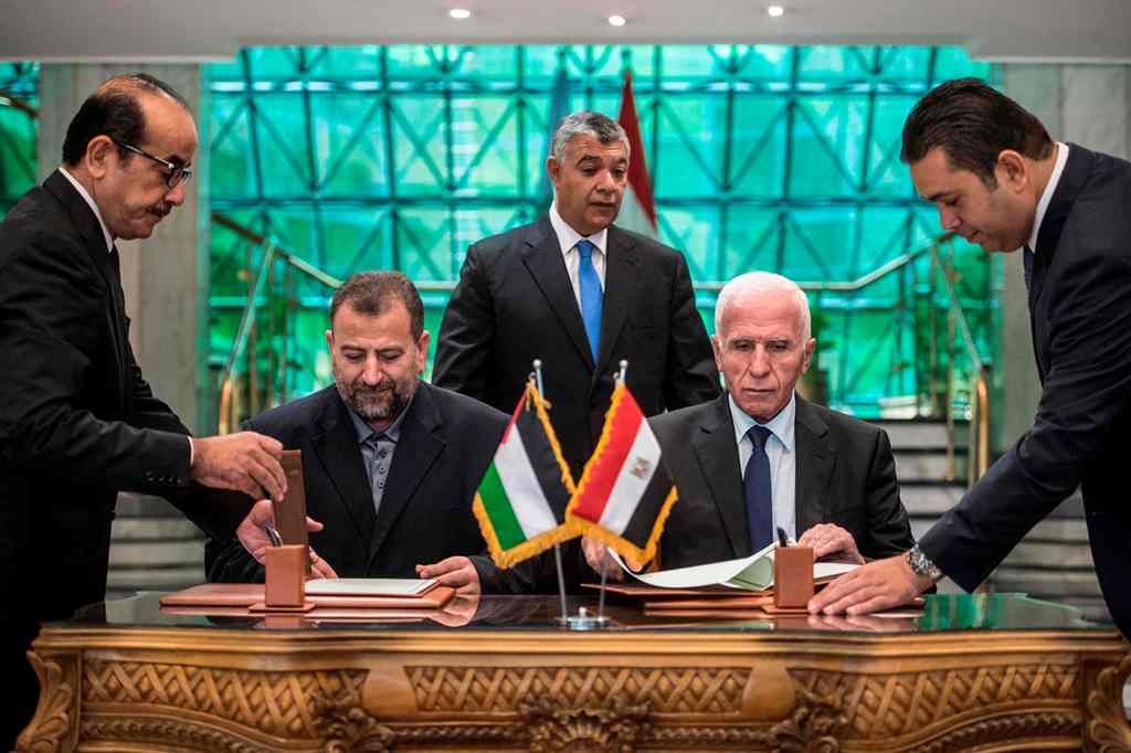 (FILES) This file photo taken on October 12, 2017 shows Fatah's Azzam al-Ahmad (R) and Saleh al-Aruri (L) of Hamas signing a reconciliation deal at the Egyptian intelligence services headquarters in Cairo, as the two rival Palestinian movements ended thei