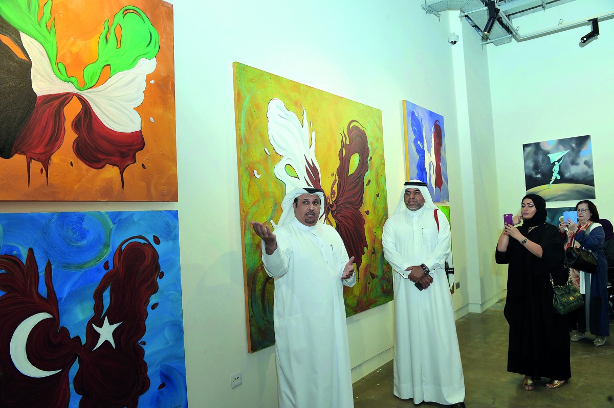 Nasser Al Attiya (left) talks about some of his paintings while Khalifa Al Obaidli (centre), Director of the Fire Station looks on, at the opening of Al Attiya’s exhibition at Doha Fire Station on Monday. Pic: Kammutty VP/The Peninsula