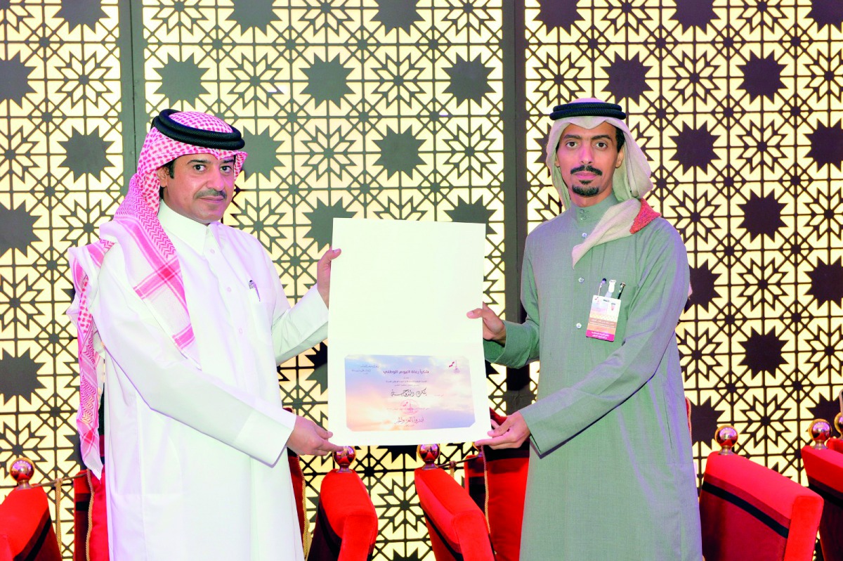 Ahmed Al Henzab, Head of Administration & Property Department at Doha Bank, receives a trophy and a plaque of appreciation on behalf of Doha Bank from Hassan AL-Ajmi from the Qatar National Day Celebrations Organising Committee at Darb Al Saai during a sp
