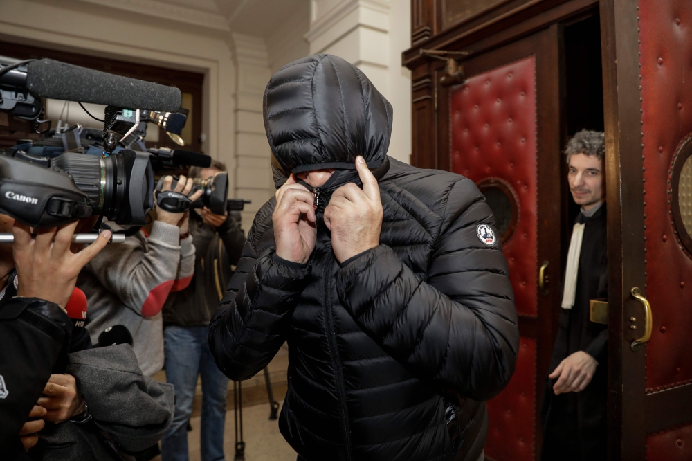 A man covers his face as he leaves the court during the first session of the 2013 Brussels Airport diamond heist case at the Brussels criminal court on January 31, 2018, in which sixteen men and three women are accused. AFP / Belga / Thierry Roge