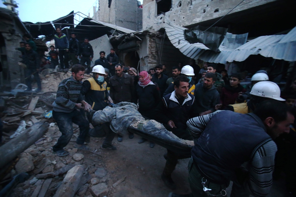 Members of Syrian civil defence forces known as the White Helmets evacuate a victim of an air strike in the rebel-held enclave of Arbin in the Eastern Ghouta near the capital Damascus on February 9, 2018. AFP / ABDULMONAM EASSA