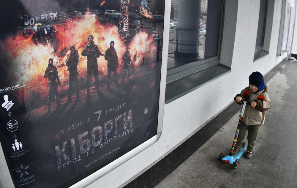 A boy passes a poster of the Ukrainian blockbuster film 