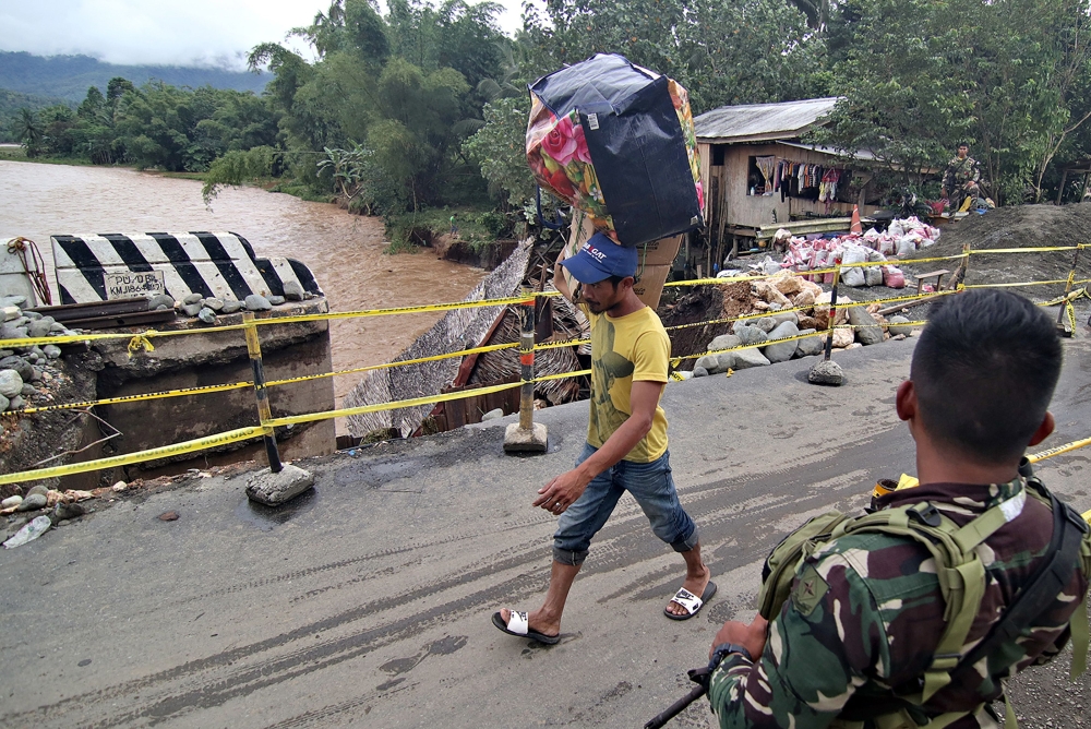 A resident carries belongings over a bridge damaged by flooding following heavy rains brought by tropical Storm Sanba in the town of Jaboanga in Agusan del Norte province on the southern island of Mindanao on February 13, 2018.  AFP / Erwin MASCARINAS
