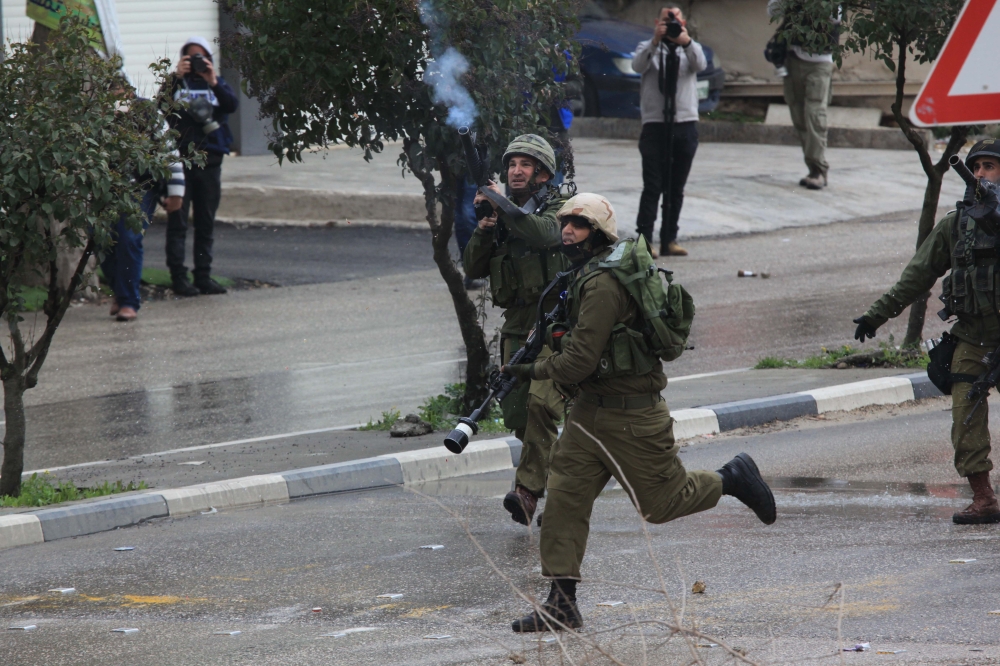 A member of Israeli security fires a tear gas canister to Palestinians during a demonstration, organized to protest Israeli authorities after a Palestinian youth Hamza Zeamire, aged 17, was killed by Israeli security forces, in Hebron, West Bank on Februa