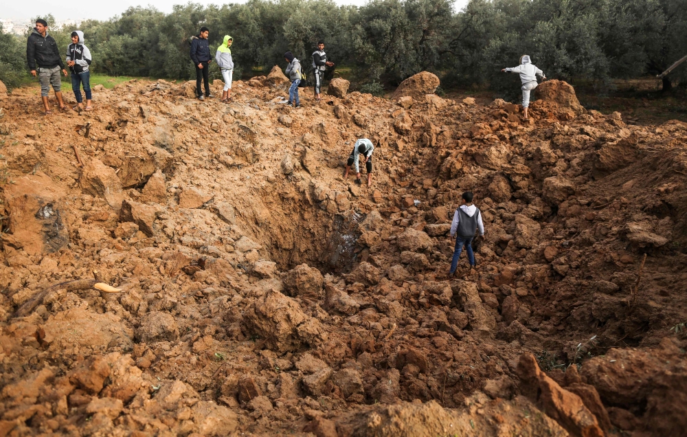 Palestinians check the site of an Israeli air strike in Gaza City on February 18, 2018. / AFP / MAHMUD HAMS 