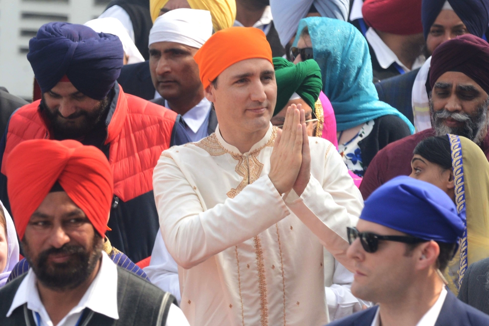 Canadian Prime Minister Justin Trudeau (C) pays his respects at the Sikh Shrine Golden temple in Amritsar on February 21, 2018. Trudeau and his family are on a week-long official trip to India. / AFP / NARINDER NANU