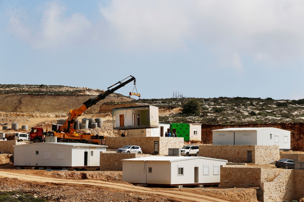 A crane lowers a caravan to the ground in Amichai, a new settlement which will house some 300 Jewish settlers evicted in February 2017 from the illegal West Bank settlement of Amona, in the Israeli occupied West Bank, February 22, 2018. Reuters/Ammar Awad