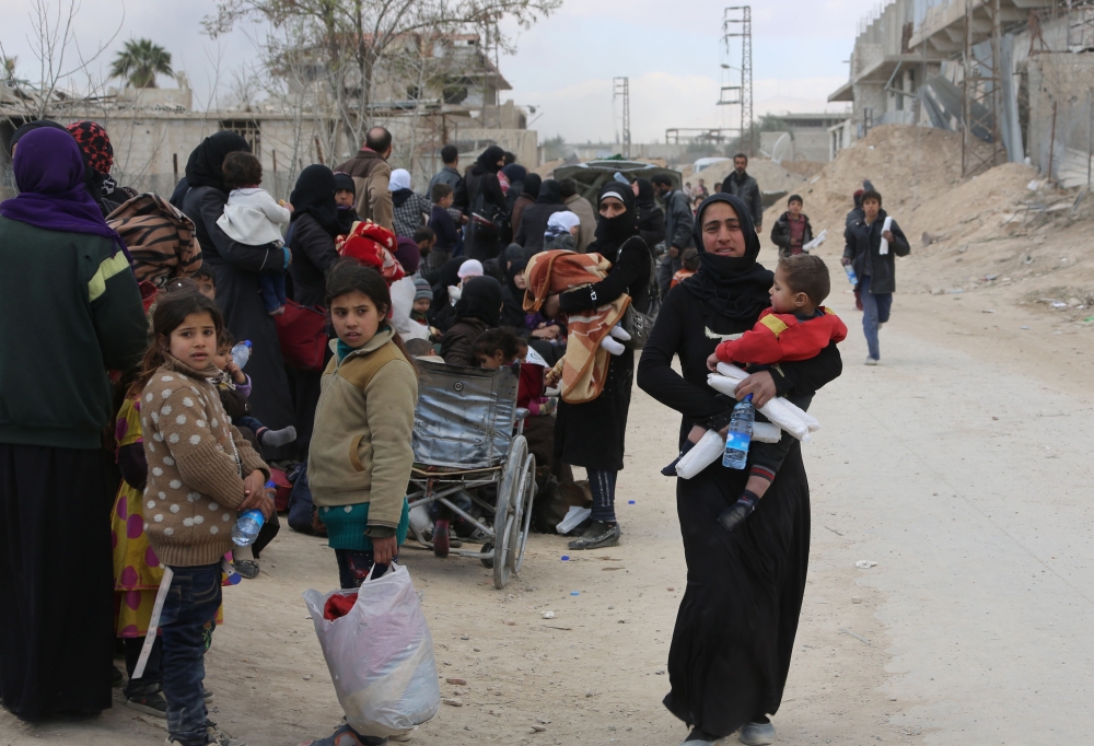 Syrians from the rebel-held Eastern Ghouta region, just outside Damascus, cross a regime-controlled corridor in Hamouria in Eastern Ghouta, after leaving the besieged enclave towards government areas on March 16, 2018. AFP
 
