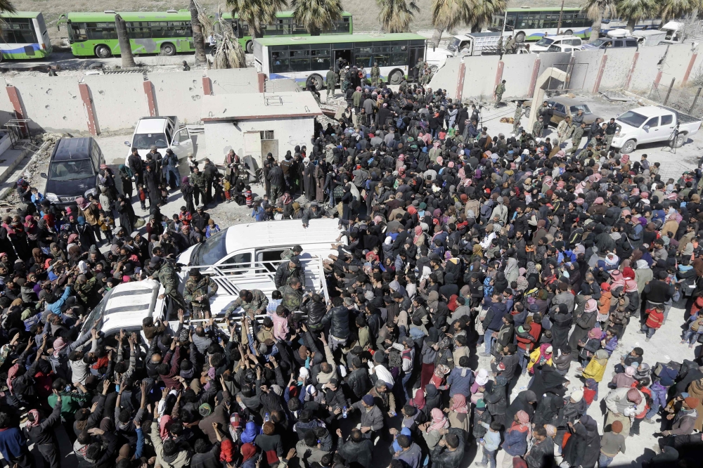 Syrian civilians, evacuated from rebel-held areas in the Eastern Ghouta, gather at a school in the regime-controlled Hosh Nasri, on the northeastern outskirts of the capital Damascus on March 16, 2018, ahead of being relocated to other areas. AFP / LOUAI 