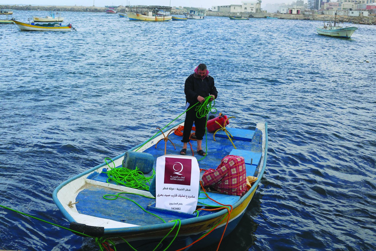 A beneficiary with his boat in Gaza provided by QC under income generating project.