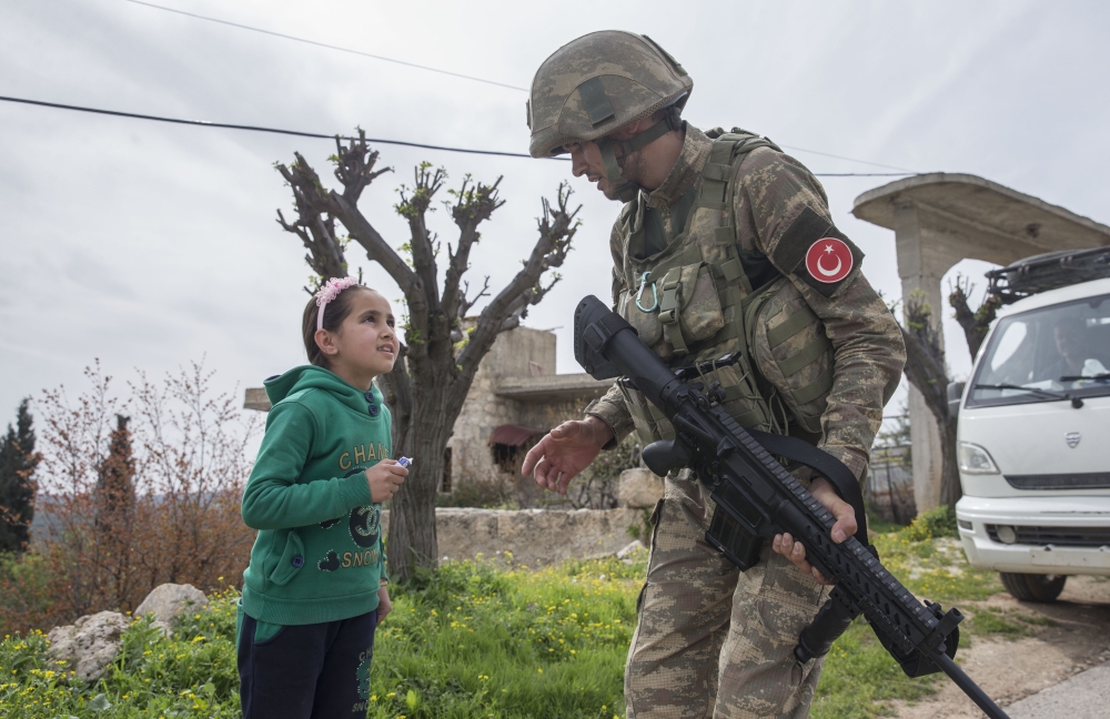 A Turkish soldier chats with a child girl in town center after Turkish Armed Forces and Free Syrian Army (FSA) took complete control of northwestern Syria's Afrin within the 