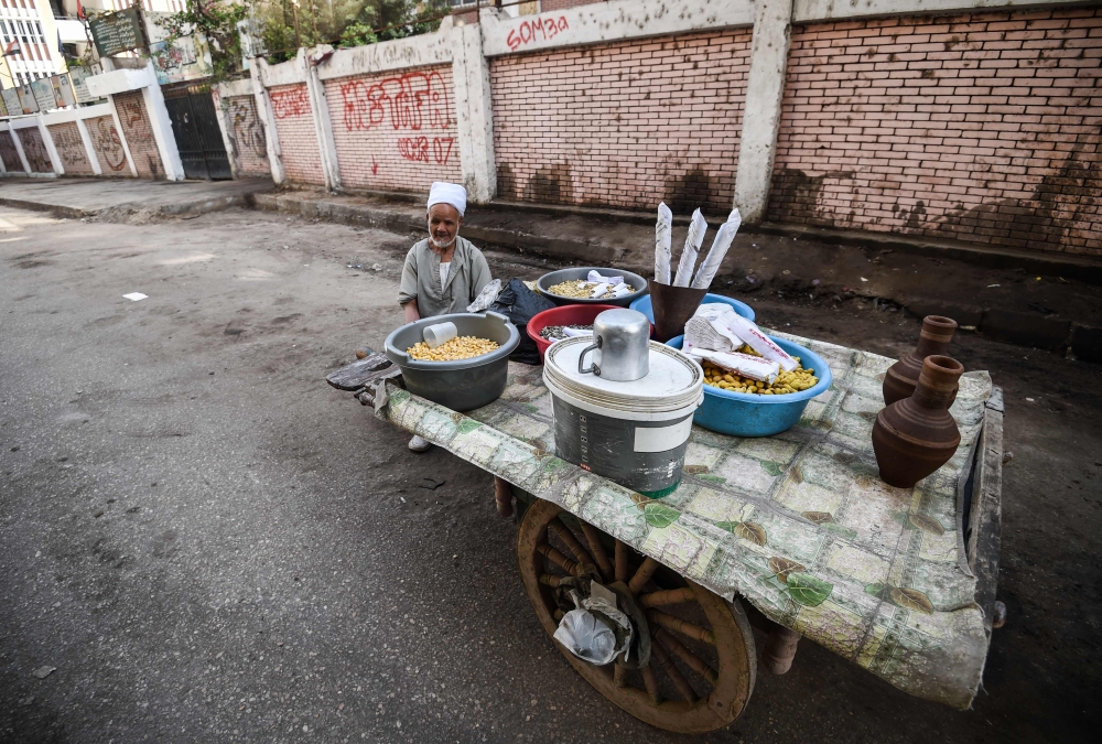An Egyptian peddlar stands next to his boiled lupine seed cart next to a school in the capital Cairo's central Al-Malek al-Saleh district on March 25, 2018. AFP / Mohamed El-Shahed