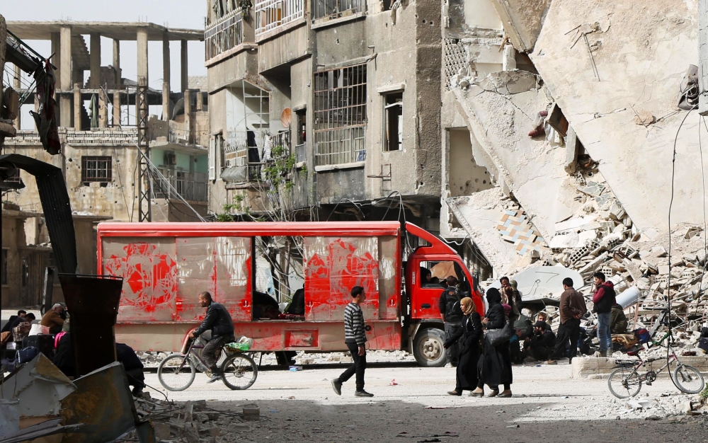 Syrians walk in the streets as they wait to be evacuated from Arbin in eastern Ghouta on March 27, 2018 after the rebel Islamist faction Faylaq al-Rahman reached a deal with Moscow, further emptying the onetime opposition bastion. AFP / Mohammed EYAD
