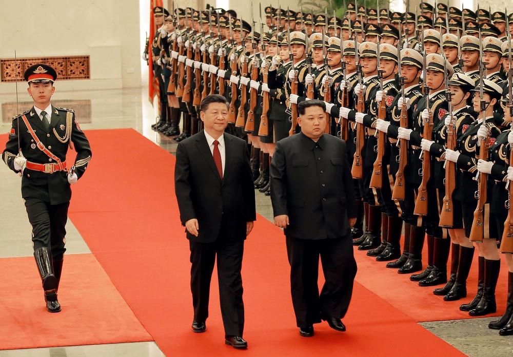 This picture from North Korea's official Korean Central News Agency (KCNA) taken on March 26, 2018 and released on March 28, 2018 shows China's President Xi Jinping (C) and North Korean leader Kim Jong Un (R) during the latter's welcoming ceremony at the 