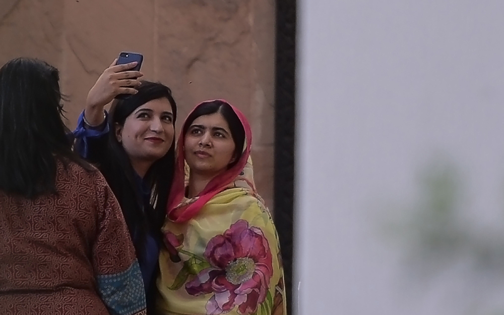 A journalist (L) takes a selfie with Pakistani activist and Nobel Peace Prize laureate Malala Yousafzai at the Serena Hotel where she is staying in Islamabad on March 30, 2018. AFP / Aamir Qureshi 