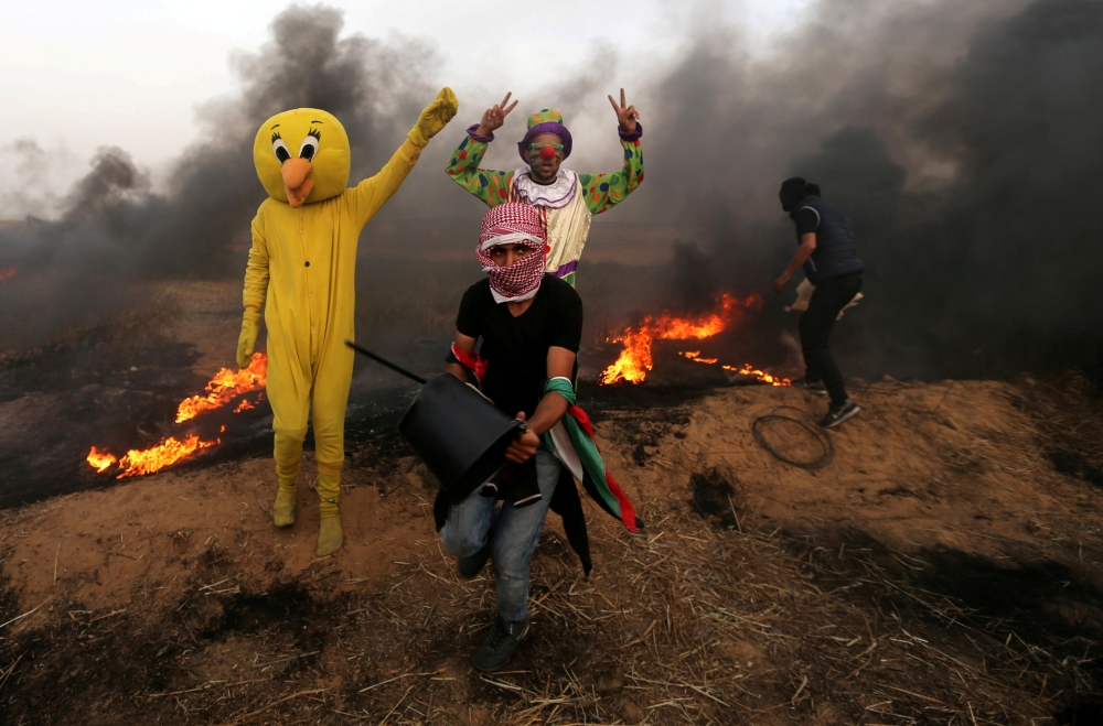 Palestinians wearing costumes are seen at the clashes scene at Israel-Gaza border in the southern Gaza Strip April 5, 2018. Reuters/Ibraheem Abu Mustafa
