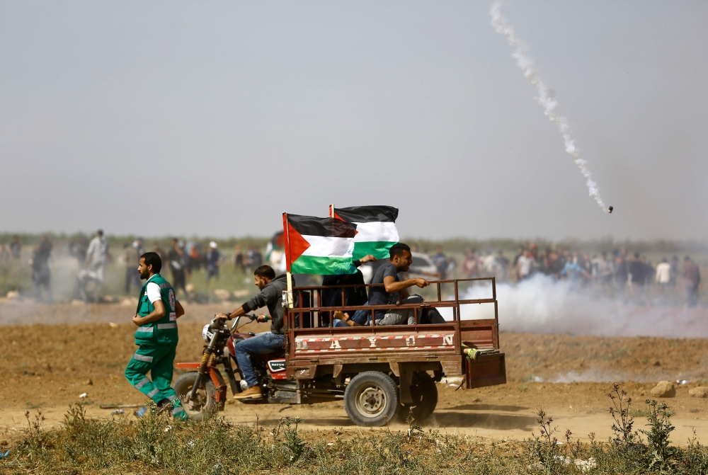 Palestinians run for cover from tears gas fired by Israeli security forces during clashes following a protest on the Israel-Gaza border east of the Jabalia refugee camp in the northern Gaza Strip on April 6, 2018.  AFP / Mohammed Abed