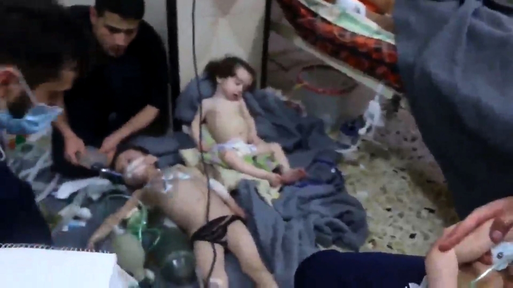 An image grab taken from a video released by the Syrian civil defence in Douma shows unidentified volunteers giving aid to children at a hospital following a reported chemical attack on the rebel-held town on April 8, 2018.  AFP Photo / Syria Civil Defenc