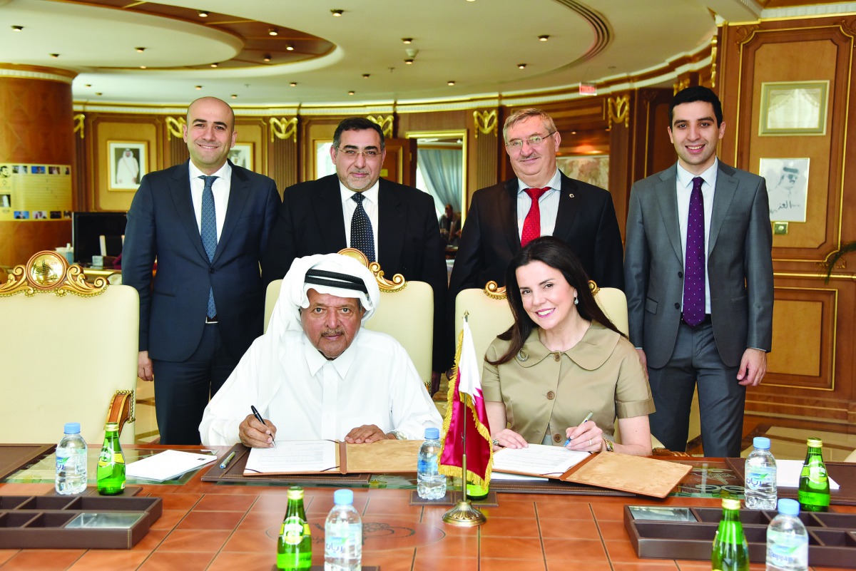 Sheikh Faisal bin Qassim Al Thani (left, sitting), Chairman of Aamal Company; and Bahar Sunman (right, sitting), member of the board of Simeks, signing agreement as other officials look on.