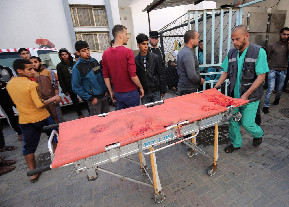 A picture taken outside the Najjar hospital in rafah shows a Palestinian paramedic pushing a blood stained stretcher which carried the body of a man who died in an explosion east of Rafah in the southern Gaza Strip, on April 14, 2018.  AFP / Said Khatib
