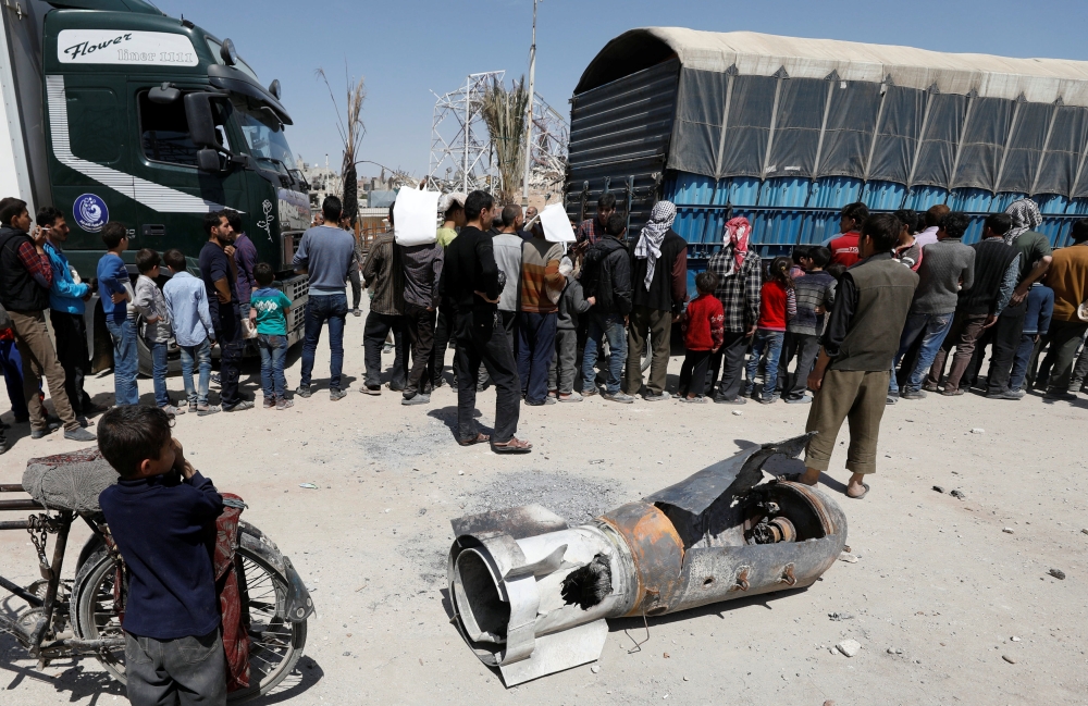 A boy stands next to the remains of a missile at the city of Douma in Damascus, Syria, April 16, 2018. REUTERS/Omar Sanadiki
