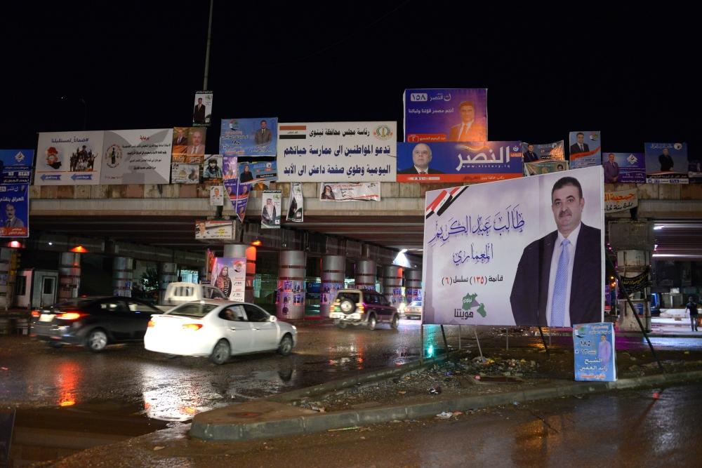 People drive under a bridge in the northern city of Mosul on April 14, 2018, bearing the campaign posters for candidates in the upcoming parliamentary elections. / AFP / Zaid al-Obeidi