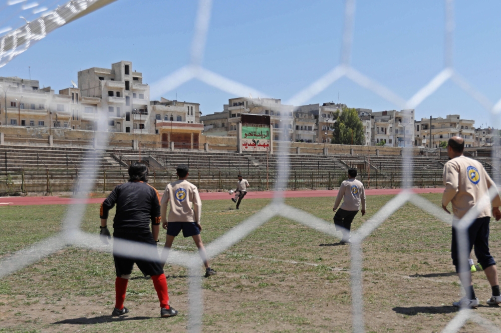 A player of the team of the Syrian Civil Defence (known as the White Helmets) kicks the ball during the first football game at Idlib's stadium since three years, in Idlib on April 25, 2018.   AFP / OMAR HAJ KADOUR
