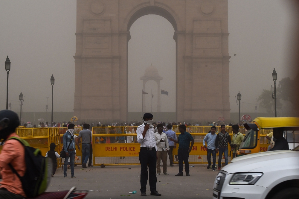 This photo taken on May 2, 2018 shows an Indian traffic policeman covering his face as he stands on duty during a dust storm in New Delhi. AFP / Chandan Khanna 