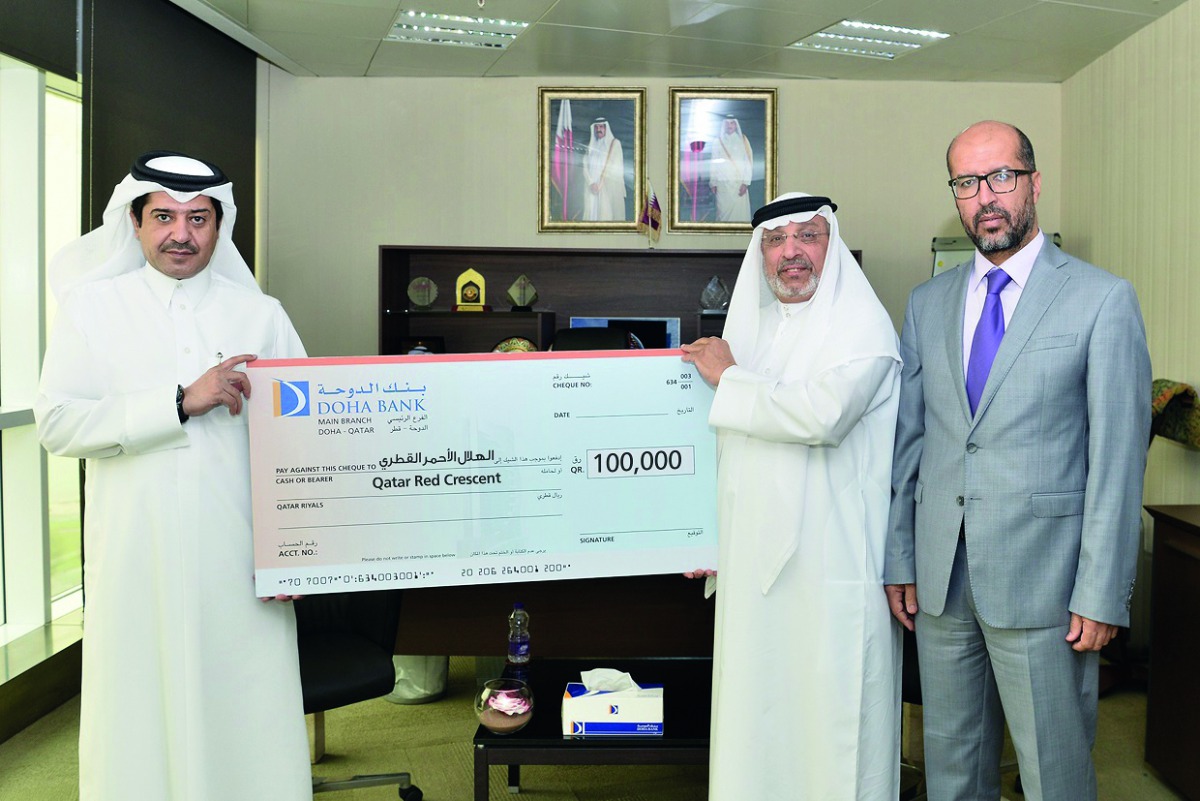 A Doha Bank officials handing over a cheque to QRCS official for its “Ramadan Iftar” campaign, 