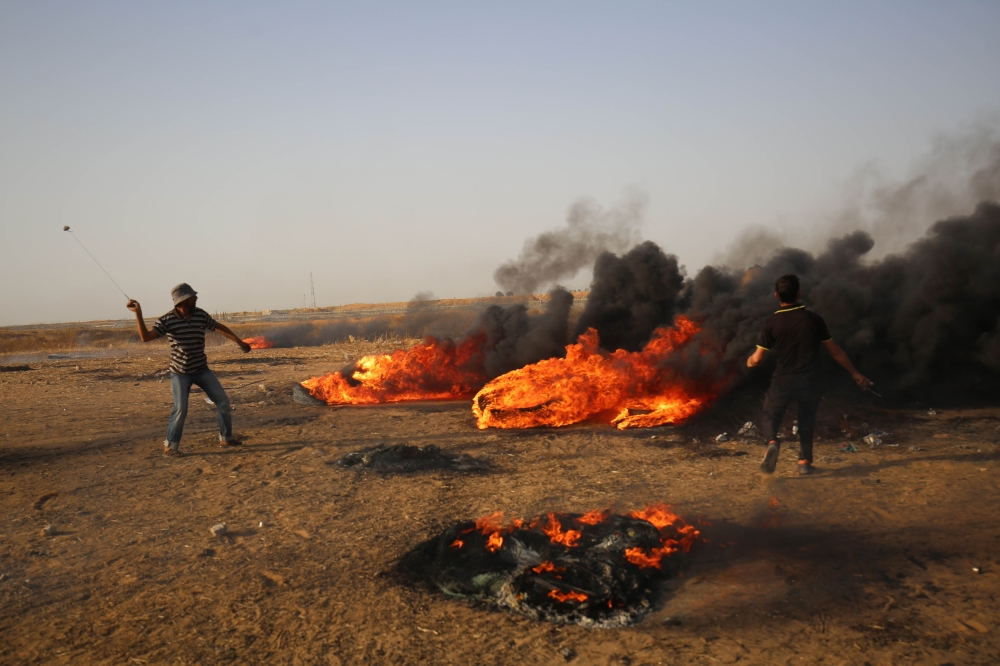 A Palestinian demonstrator uses a slingshot during clashes with Israeli forces along the border with the Gaza strip east of Khan Yunis on May 18, 2018. AFP / Said Khatib