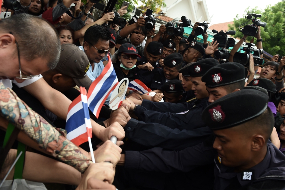 Demonstrators attempt to break thru a phalanx of police outside Thammasat University during a protest to mark the fourth year of junta rule in Bangkok on May 22, 2018. AFP / LILLIAN SUWANRUMPHA