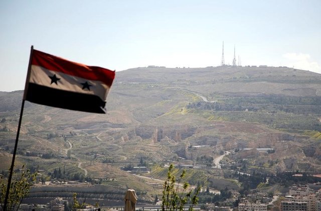 A Syrian national flag flutters as Qasioun mountain is seen in the background from Damascus, Syria. REUTERS/Omar Sanadiki