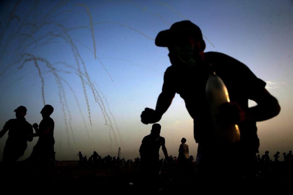  Palestinians run for cover from tear gas shot by Isreali forces during a demonstration along the border between Israel and the Gaza strip, east of Gaza City, on May 25, 2018. / AFP / MOHAMMED ABED
 