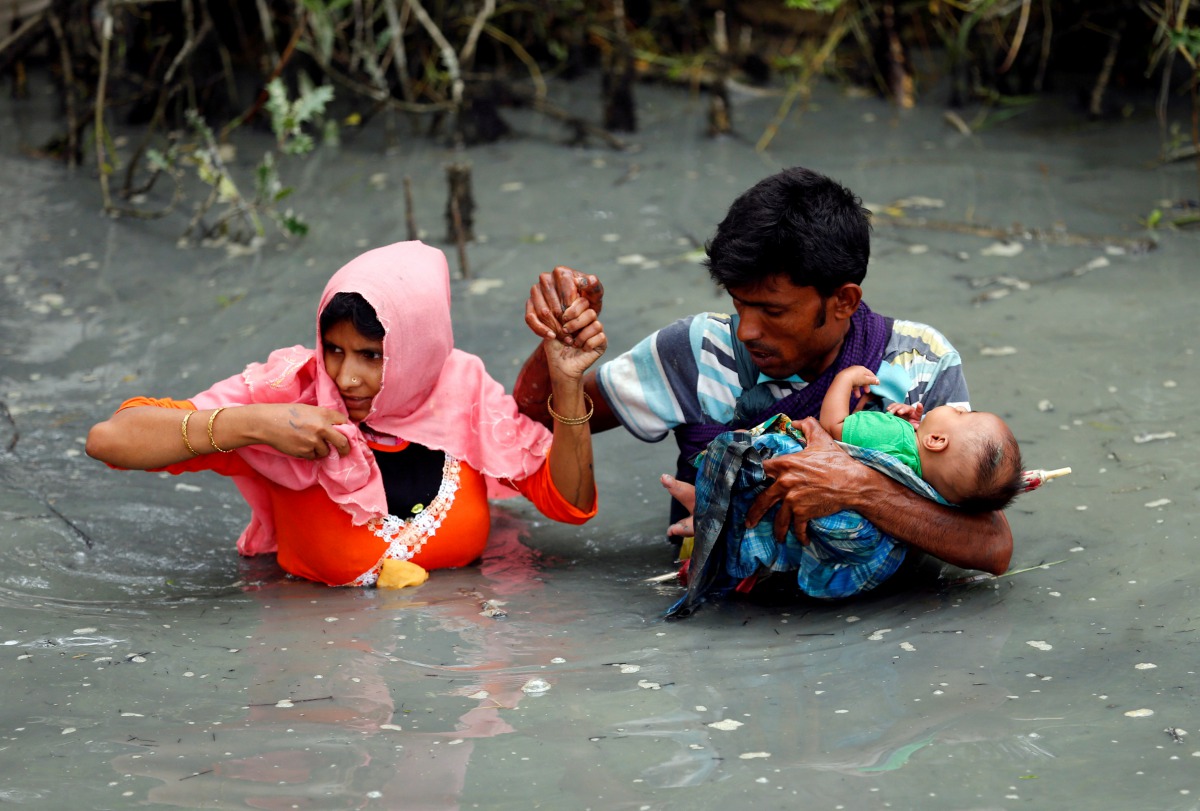 FILE PHOTO: Rohingya refugees carry their child as they walk through water after crossing border by boat through the Naf River in Teknaf, Bangladesh September 7, 2017. (Reuters / Mohammad Ponir Hossain) 