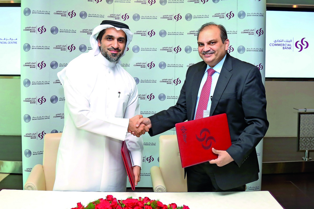 QFC and Commercial Bank officials shaking hands after the signing ceremony.