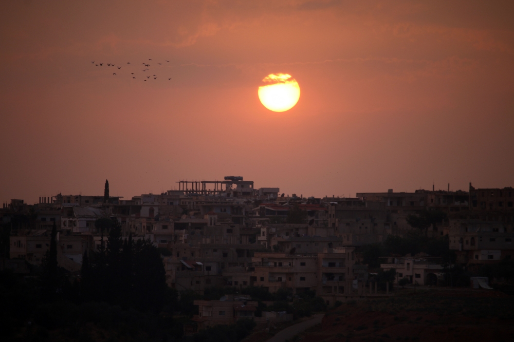 A general view shows the sun setting over a rebel-held area in the southern Syrian city of Daraa on May 28, 2018. / AFP / Mohamad ABAZEED
