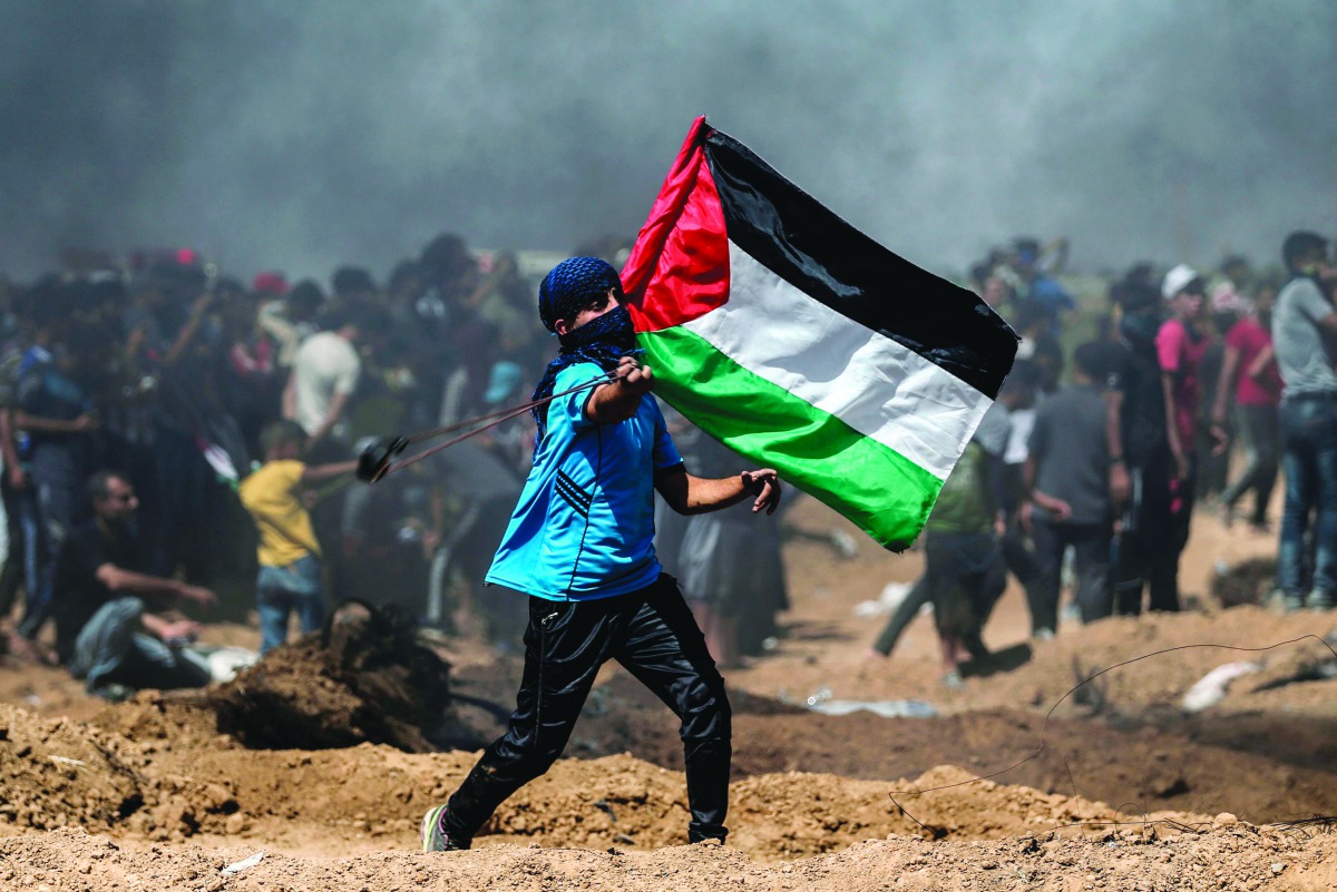 A Palestinian protestor waves his national flag during a demonstration along the border with Israel east of Jabalia in the central Gaza Strip on June 8, 2018.  AFP / Mohammed Abed