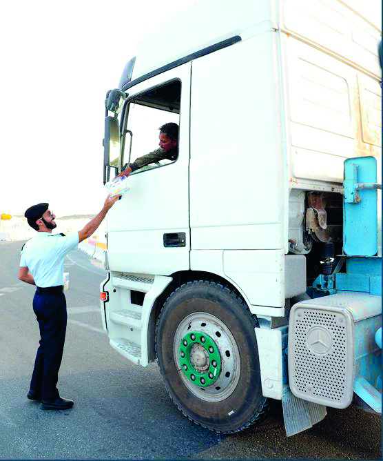 A police officer distributes Iftar meal to a motorist at Al Mazroua road. 