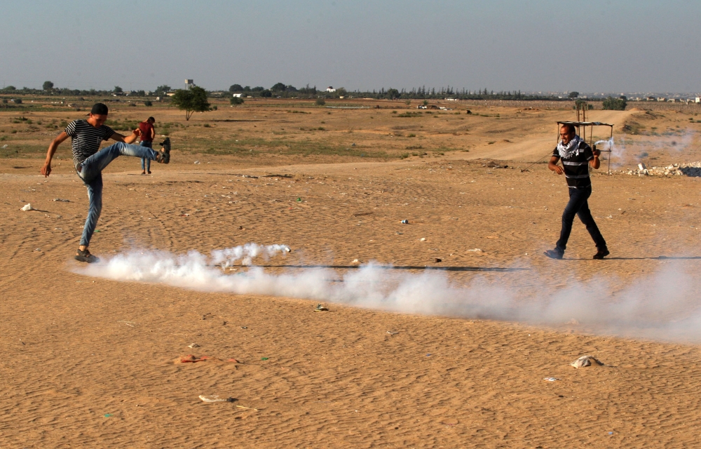  A Palestinian kicks a tear gas canister launched by Israeli soldiers as they intervened in a demonstration held within the 